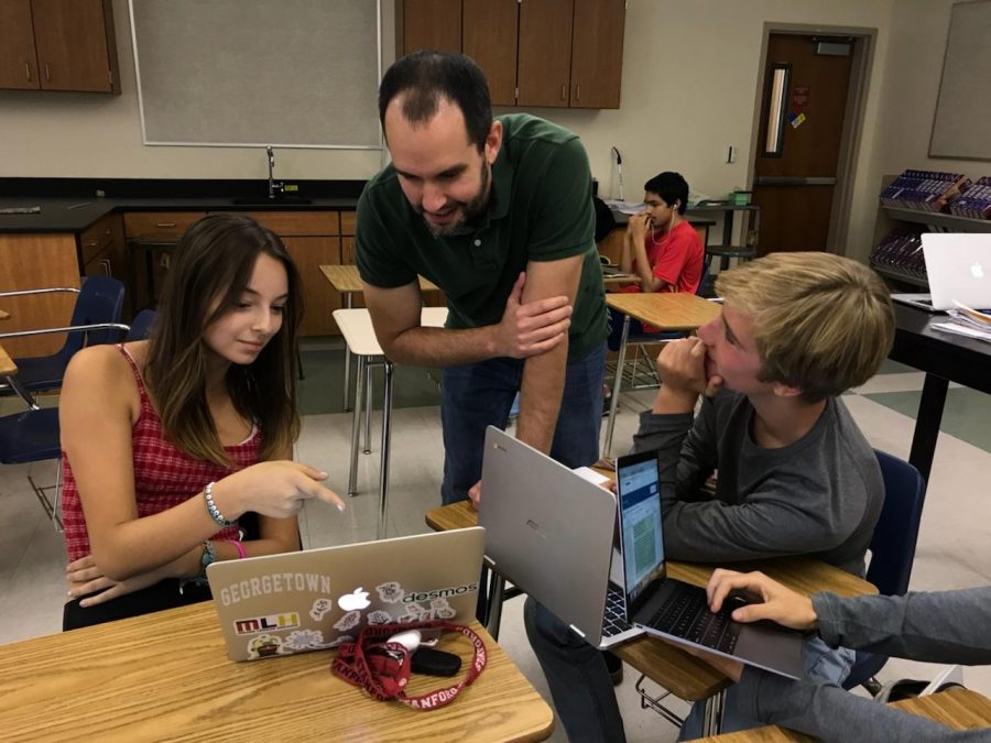 Olah discusses questions with his AP Biology students Naomi Jekcer-Eshel (left) and Nathan Strope (right). Although he enjoys teaching, one benefit of teaching fewer classes is the reduced grading, according to Olah. Photo by Anna Tomz
